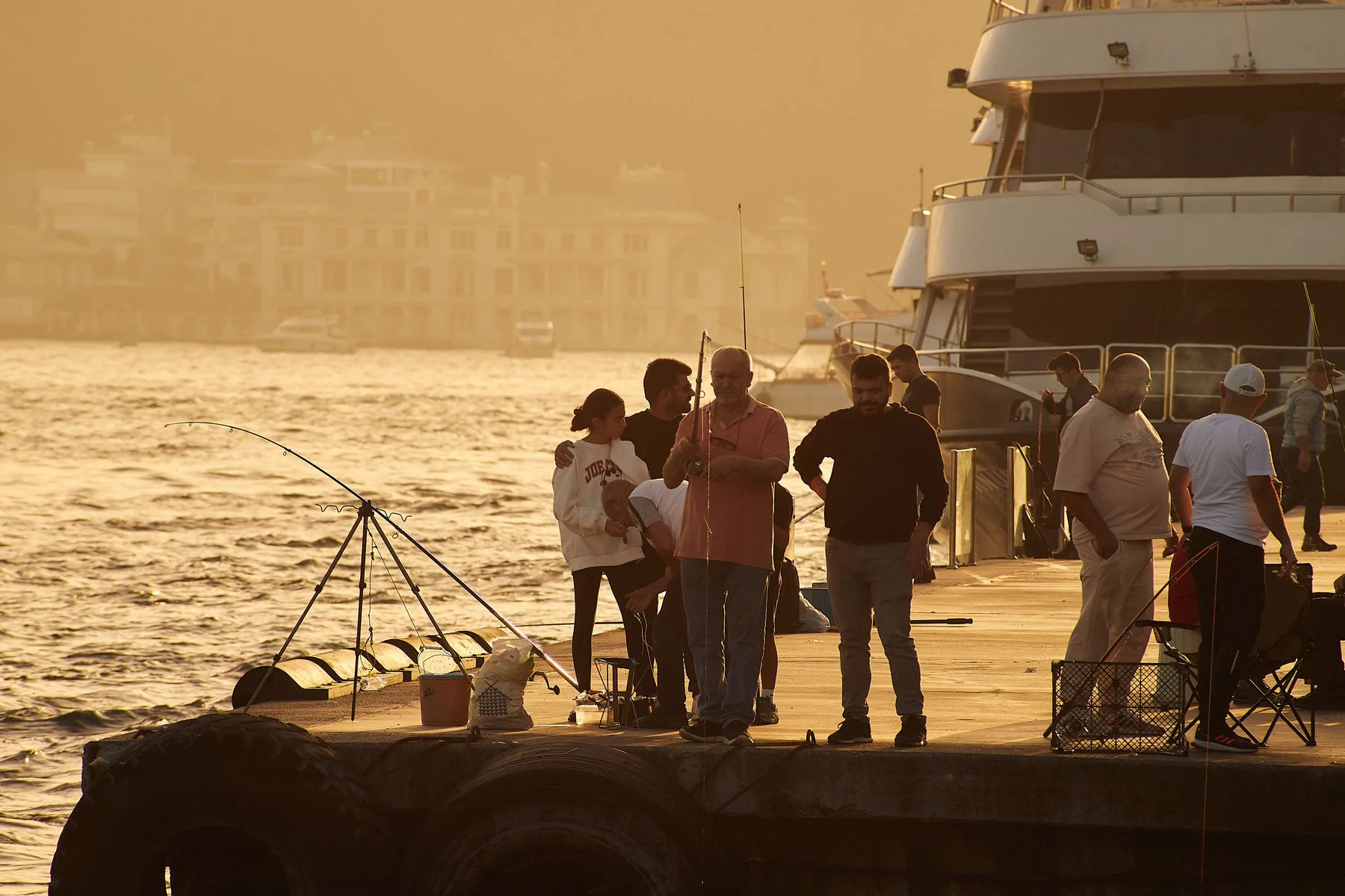 People fishing from a waterfront pier at sunset