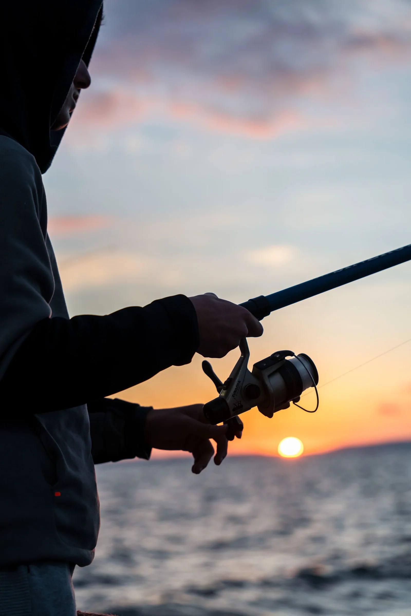 An angler silhouetted against the evening sea